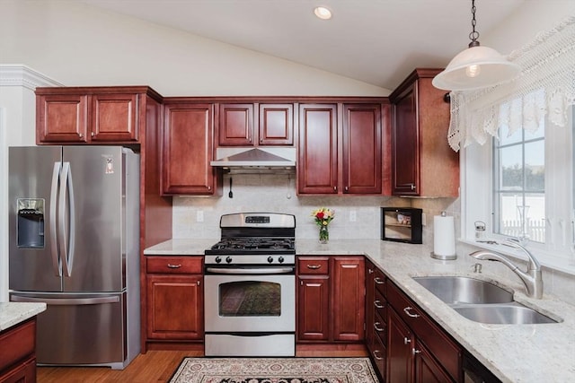 kitchen with appliances with stainless steel finishes, vaulted ceiling, a sink, dark brown cabinets, and under cabinet range hood