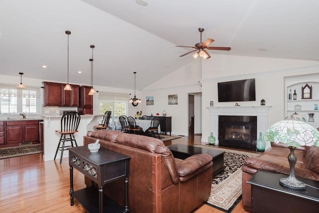 living room with lofted ceiling, light wood-style flooring, a ceiling fan, and a fireplace with flush hearth