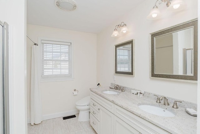 full bath featuring toilet, double vanity, baseboards, and a sink