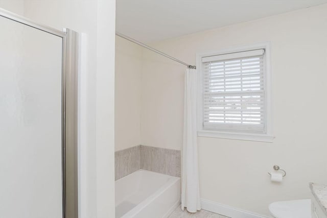 bathroom featuring toilet, baseboards, a washtub, and a shower with shower curtain