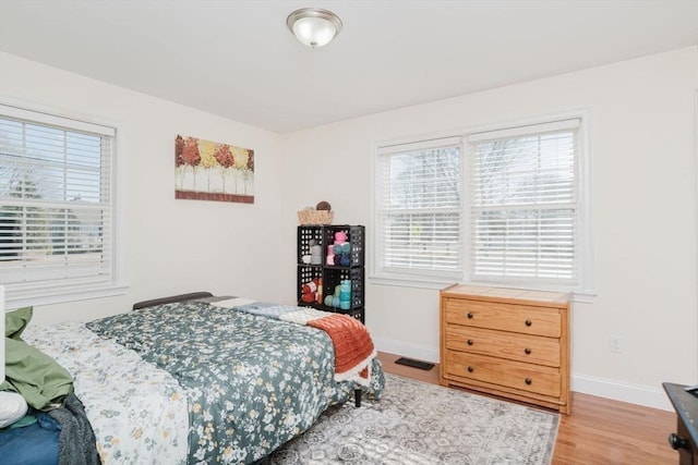 bedroom with visible vents, baseboards, and wood finished floors