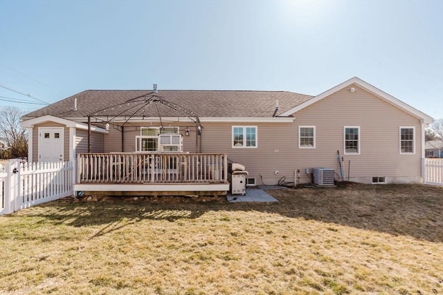 back of house featuring a shingled roof, a lawn, fence, a deck, and cooling unit