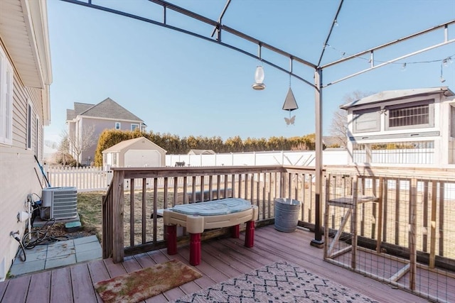 deck with a fenced backyard, an outdoor structure, a storage unit, and central air condition unit