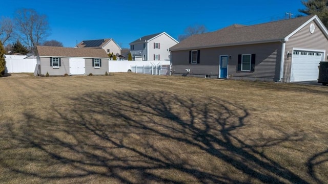 exterior space with a garage, fence, an outdoor structure, and a yard