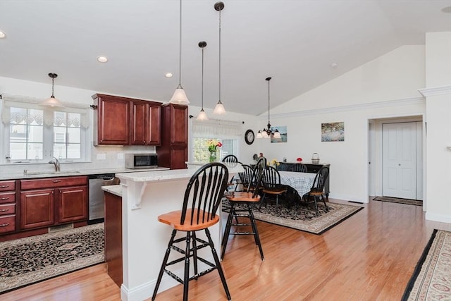 kitchen featuring stainless steel appliances, a healthy amount of sunlight, a sink, and a kitchen breakfast bar