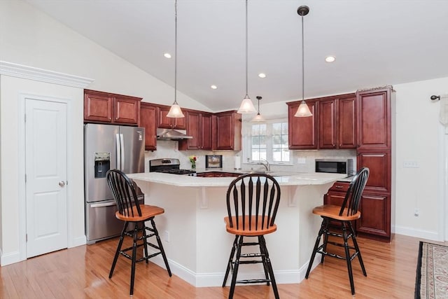 kitchen with light wood-style flooring, under cabinet range hood, stainless steel appliances, light countertops, and a center island