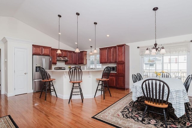 kitchen with under cabinet range hood, a breakfast bar area, stainless steel appliances, and light countertops