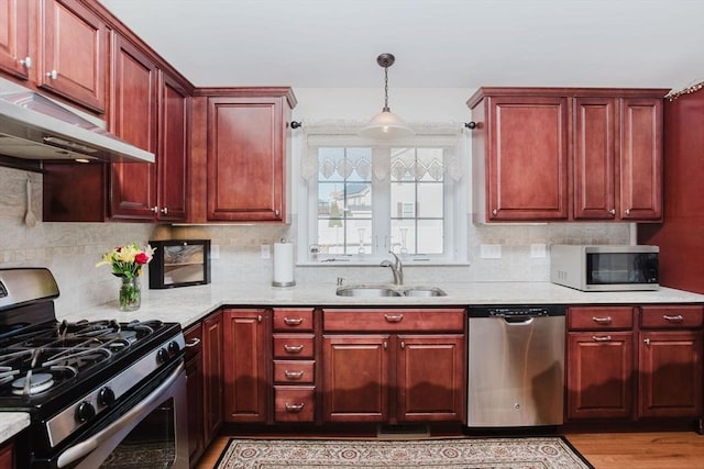 kitchen featuring appliances with stainless steel finishes, a sink, under cabinet range hood, and dark brown cabinets