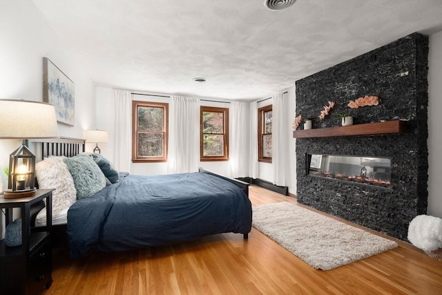 5 Crescent Ln, Sudbury, MA 01776 - bedroom with visible vents, a multi sided fireplace, and wood finished floors