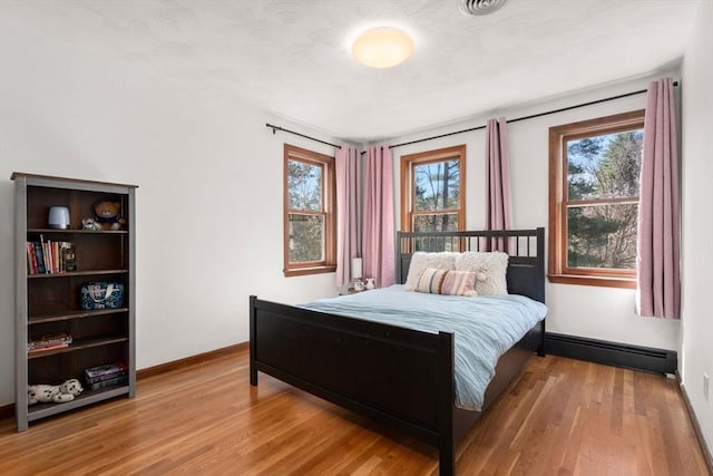 5 Crescent Ln, Sudbury, MA 01776 - bedroom featuring a baseboard heating unit, baseboards, and wood finished floors