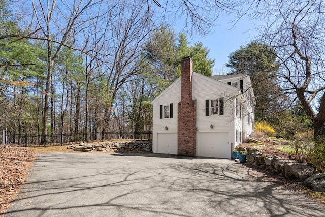 5 Crescent Ln, Sudbury, MA 01776 - view of side of home featuring a chimney, aphalt driveway, a garage, and fence