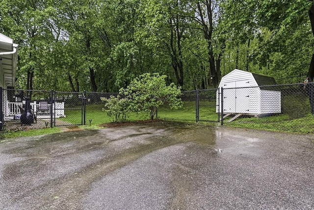 view of yard with a gate, asphalt driveway, a shed, and an outdoor structure