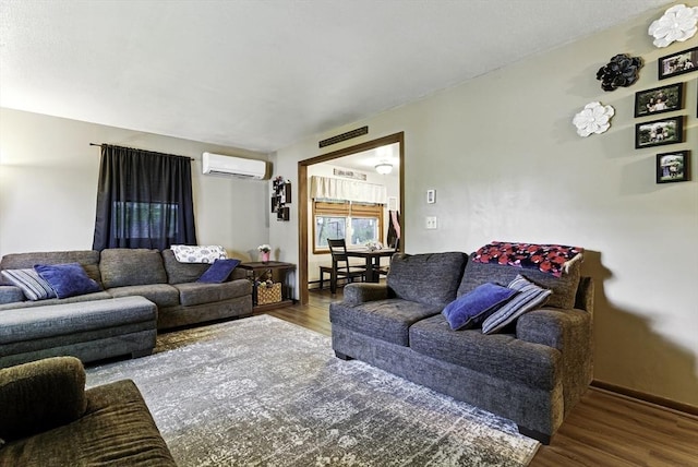 living area with a wall unit AC and wood finished floors