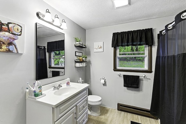 full bath featuring wood finished floors, a baseboard radiator, vanity, a textured ceiling, and toilet