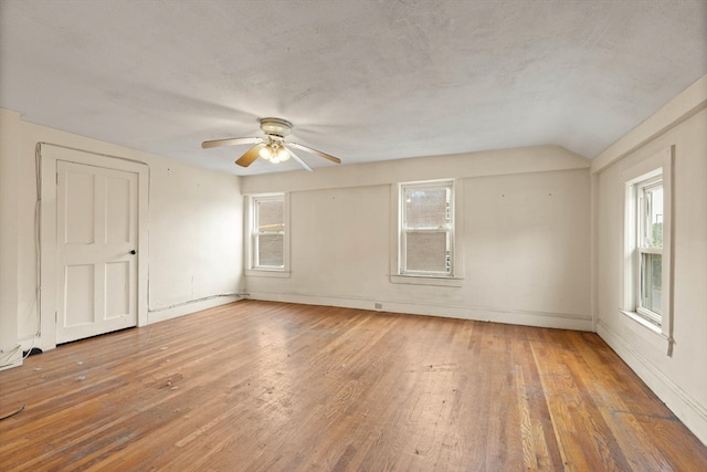 empty room with ceiling fan, hardwood / wood-style flooring, vaulted ceiling, and a textured ceiling