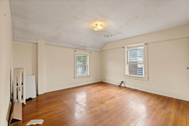 empty room with a textured ceiling, hardwood / wood-style flooring, and a wealth of natural light