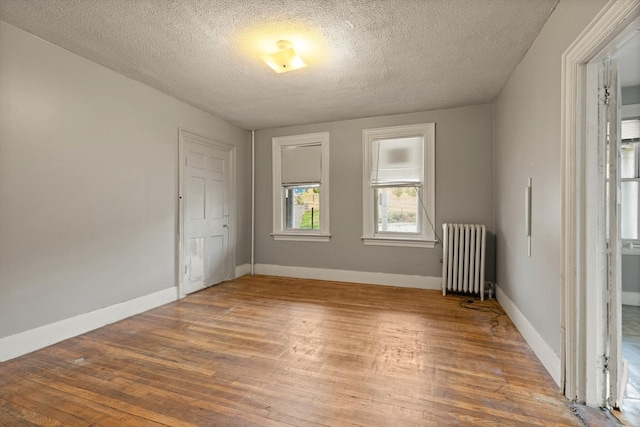 empty room featuring a textured ceiling, radiator, and hardwood / wood-style flooring