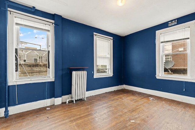 empty room featuring wood-type flooring and radiator heating unit