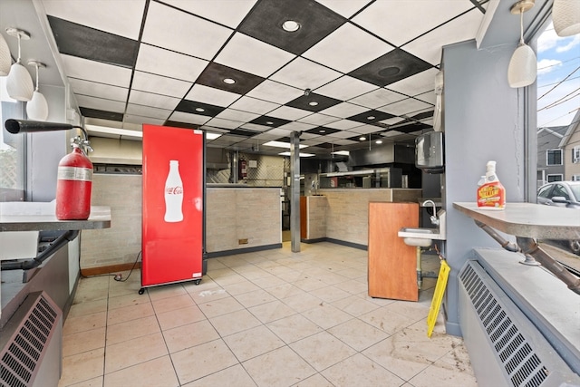 kitchen with a paneled ceiling and light tile patterned floors