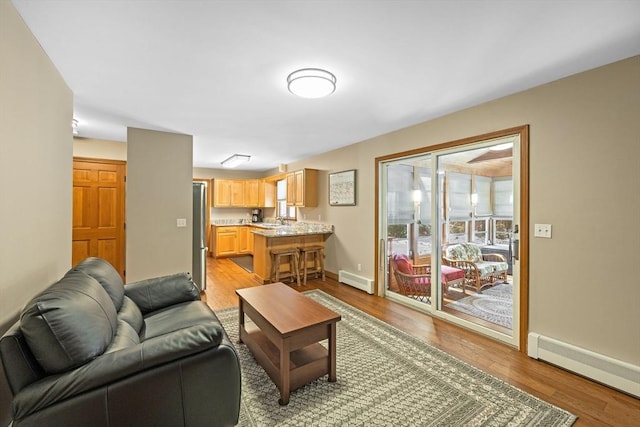 living room featuring a baseboard radiator, sink, and light hardwood / wood-style flooring