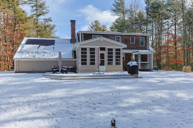 snow covered rear of property with a sunroom and central air condition unit