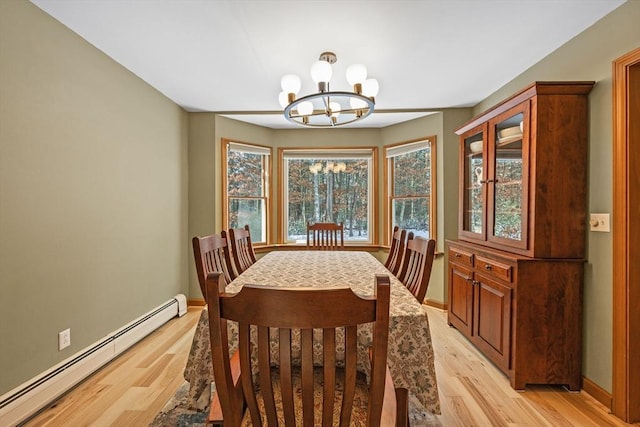 dining space with an inviting chandelier, a healthy amount of sunlight, light hardwood / wood-style flooring, and a baseboard heating unit