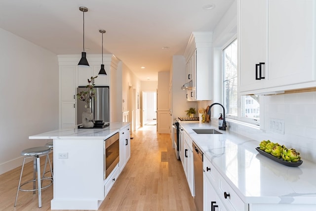 kitchen featuring white cabinets, pendant lighting, sink, a kitchen island, and appliances with stainless steel finishes