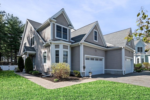 view of front of house with aphalt driveway, roof with shingles, fence, and a front yard