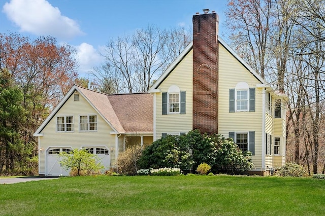 view of front of home featuring a garage, driveway, a front yard, and a chimney
