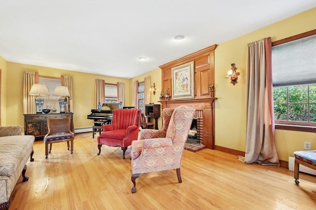 living area featuring baseboards, a fireplace, a baseboard heating unit, and light wood-type flooring