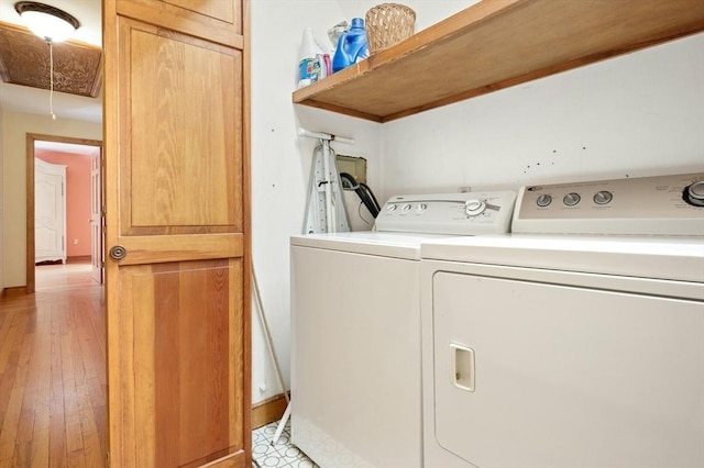 washroom featuring laundry area, attic access, baseboards, light wood-type flooring, and washer and clothes dryer