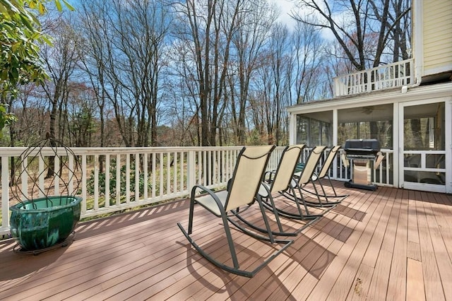 wooden deck featuring a sunroom and area for grilling