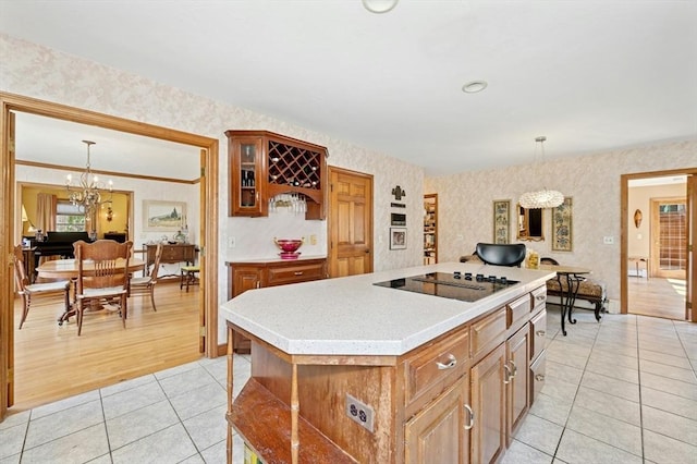 kitchen with a notable chandelier, light countertops, black electric cooktop, wallpapered walls, and light tile patterned floors