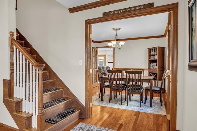 dining space featuring an inviting chandelier, crown molding, and light wood-type flooring