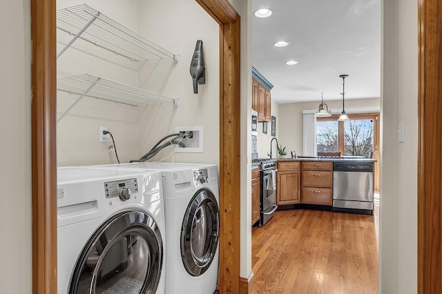 clothes washing area with washer and dryer and light wood-type flooring