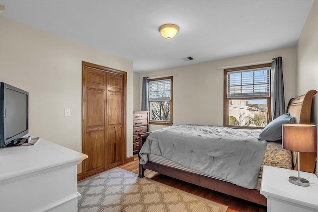 bedroom with multiple windows, light hardwood / wood-style floors, and a closet