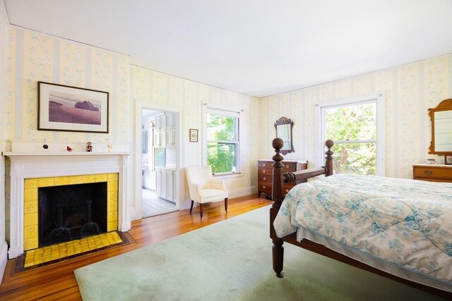 21 Waterston Rd, Newton, MA 02458 - bedroom featuring wood finished floors, wallpapered walls, a tile fireplace, and multiple windows