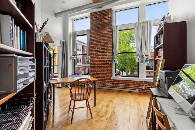 281 Essex St Unit 206, Salem, MA 01970 - home office with a baseboard radiator, wood-type flooring, a towering ceiling, and brick wall
