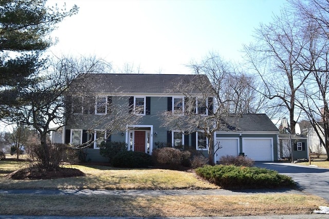 colonial-style house with aphalt driveway and a garage