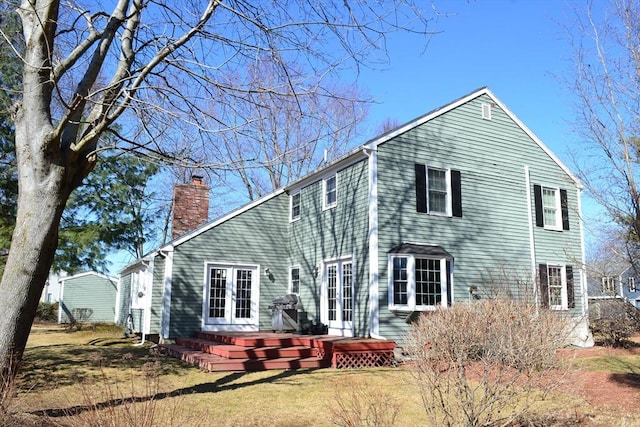 rear view of house featuring french doors, a yard, a deck, and a chimney