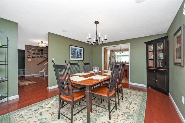 dining space featuring stairway, a notable chandelier, wood finished floors, and baseboards