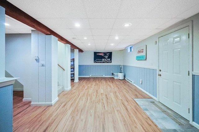 interior space with a wainscoted wall, a baseboard radiator, stairs, and wood finished floors