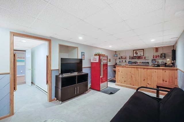 living room featuring a baseboard heating unit, a drop ceiling, light carpet, wainscoting, and recessed lighting