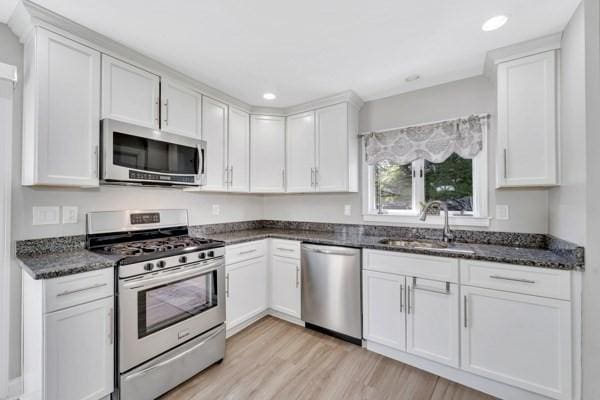 135 Pine Grove Ave, Lynn, MA 01904 - kitchen featuring appliances with stainless steel finishes, a sink, white cabinets, light wood-style flooring, and dark stone countertops