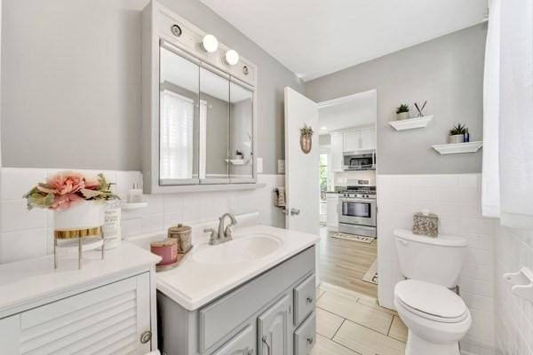 135 Pine Grove Ave, Lynn, MA 01904 - bathroom featuring tile walls, vanity, toilet, and a wainscoted wall