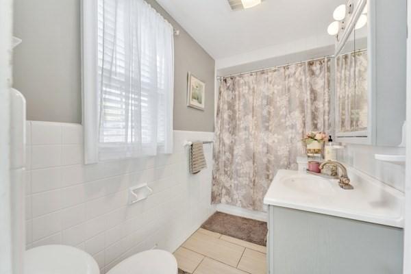 135 Pine Grove Ave, Lynn, MA 01904 - bathroom with toilet, vanity, tile walls, wainscoting, and tile patterned floors