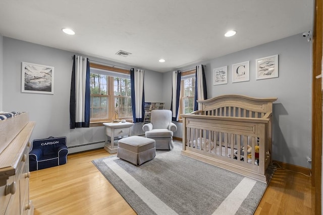 bedroom featuring wood finished floors, visible vents, recessed lighting, and a baseboard heating unit