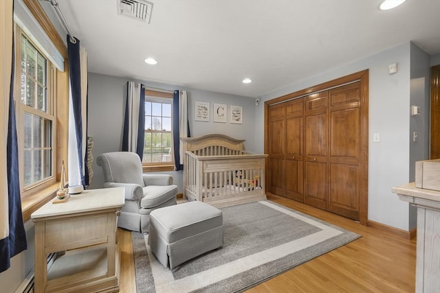bedroom with recessed lighting, a closet, light wood finished floors, baseboards, and visible vents