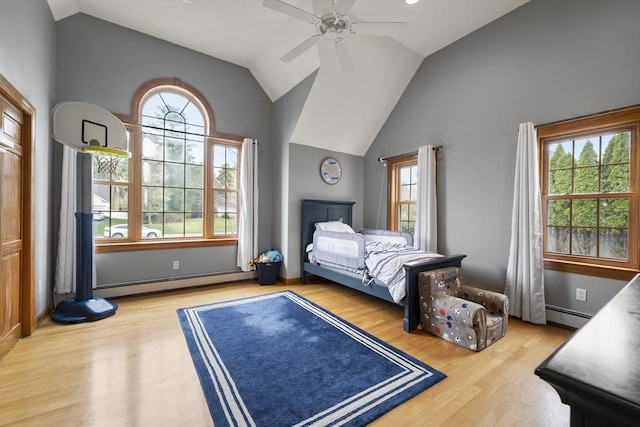bedroom featuring a baseboard heating unit, multiple windows, and wood finished floors
