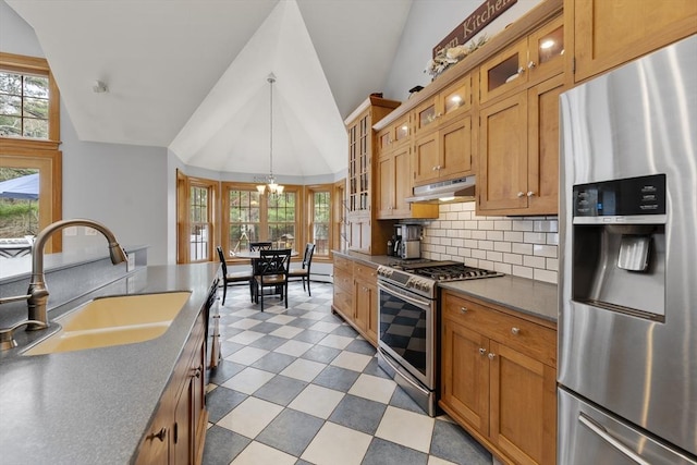kitchen with a sink, under cabinet range hood, vaulted ceiling, appliances with stainless steel finishes, and plenty of natural light